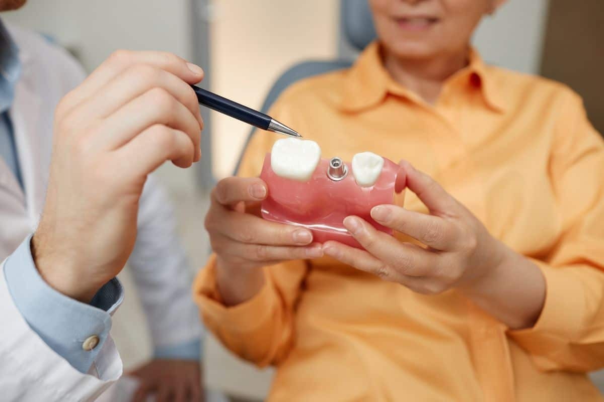 Dentist showing dental implant model to patient in Stuart dental practice.